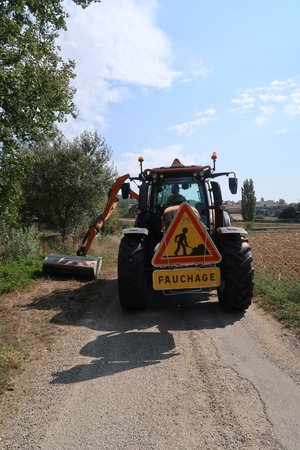 tracteur en train de faucher un accotement avec panneau travaux de fauchage 